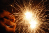 Photograph showing sparks like fireworks, with a hand in the background.
