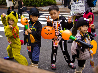 Four small children, two holding jack-o'-laterns, pose in their Halloween costumes.