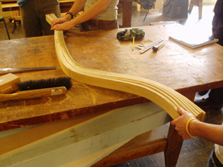 A wood-bending demonstration.  Three students bending wooden strips with their hands.