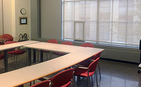 A classroom with moveable tables and chairs with a seating capacity of 18 and an A/V system.
