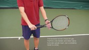 The racket is held in the right hand, pointing left across the body, with the strings parallel to the net and the palm facing the ground.