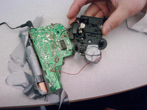Photo of hand holding a tape player circuit board and mechanism.