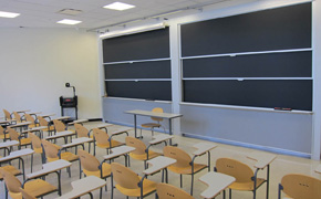 A medium-sized classroom with student desks and several chalkboards.