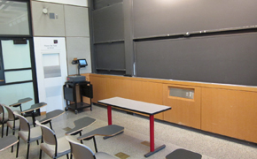 Picture of classroom with 16 tablet-style desks and and sliding chalkboards.