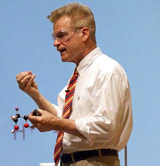 A photo of Dr. John Dolhun, the course instructor, lecturing and holding a molecular model.