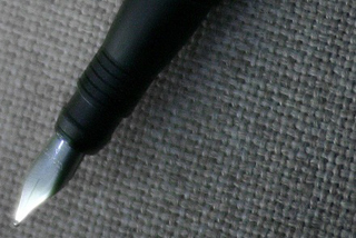 Photograph of a fountain pen in front of a grey fabric background.
