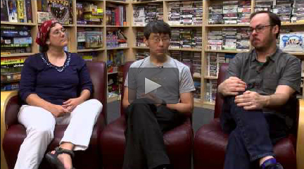 An image of instructors Sara Verrilli, Philip Tan, and Richard Eberhardt taken from an interview. The three are are seated side-by-side in front of large bookcases filled with various games.