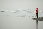 Lone figure on shoreline viewing icebergs