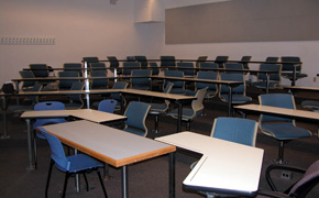 A photograph of  a classroom looking out over five rows of seats.