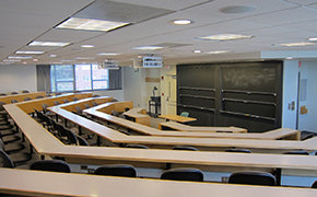 Classroom with tiered seating and sliding chalkboards.