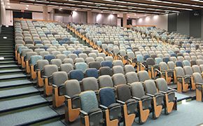 Lecture hall with tiered seating and tablet armchairs.