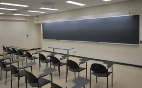 Classroom with blackboard in front and tablet arm chairs arranged in rows.