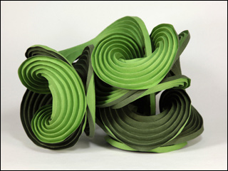 Green paper folded along multiple curved creases to form curved fins of a sculpture.