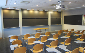 Classroom with sliding chalkboards and separate tablet armchairs.