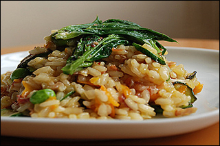 : A mound of rice sits on top of a white plate.  A large leafy green vegetable sits on top of the rice.