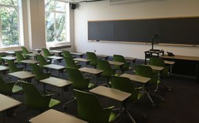 A classroom with approximately thirty green armchairs.