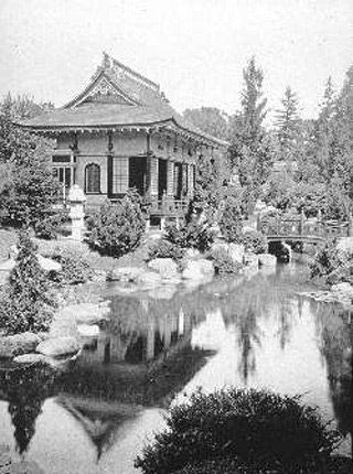 A black and white photo of a stream with a bridge, and a pagoda.