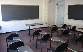 Classroom with four rows of tablet desks facing a chalkboard.