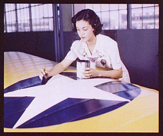 Woman painting American insignia on airplane wings, 1942.