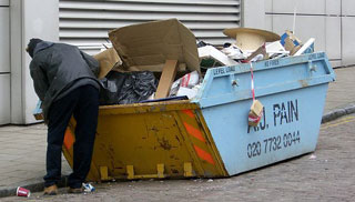 A man rummaging through a dumpster.