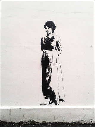 A black stencil of Mary Wollstonecraft painted on a white wall.