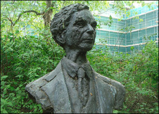 Green foliage surrounds a bust of a man.
