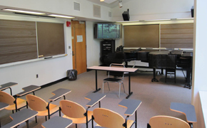 Photo shows the modern tablet armchairs, blackboards that include staves, display, and audio components at the front of the classroom.