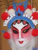 Zooming in to show details of the face and crown, with decorative elements made of foam shapes, beads on pipe cleaners, rhinestones and glitter, and large red and white pompoms.