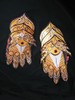 A pair of gauntlets, painted yellow with black and white accents to create intricate patterns on the foam. White and red rhinestones give a bit of flash.