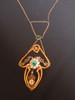 Costume jewelry segments are framed with gold piping  and attached to a green stone set in gold.