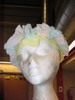 A foam head has alternating blue and pink cupcake liners arching across its brow, with flattened yellow liners dipping down onto the forehead.