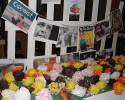 Multi-colored paper roses lie in front of photos of people of different ethnicities.