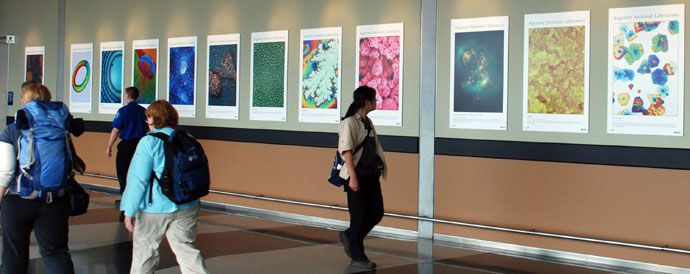 A woman walking and looking at scientific photographs on the wall of a hallway.