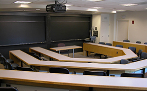 A photograph of a lecture hall at MIT, facing the chalkboard. The room has tiered seating.