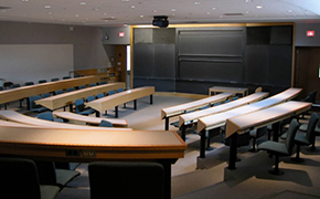 Tiered fixed furniture tables arranged in a u-shape facing blackboards at the front of the room.