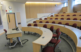 A raked, amphitheater-style lecture hall with five rows of seating and a lectern in front.