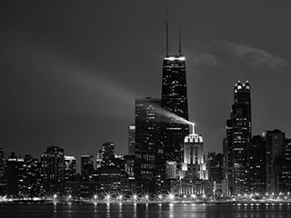 A black and white photo of the Chicago skyline at night.