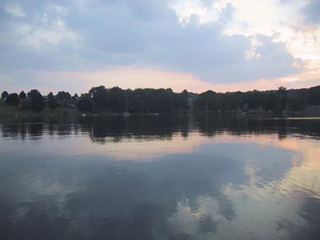 A photo of a calm lake with trees in the distance.