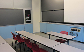 A small, multi-row room with blackboards on two sides.