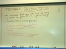 Notes on a whilteboard explain testable predictions.