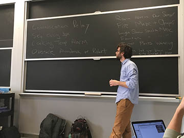 A man standing in front of a blackboard in a classroom during an idea brainstorming session.